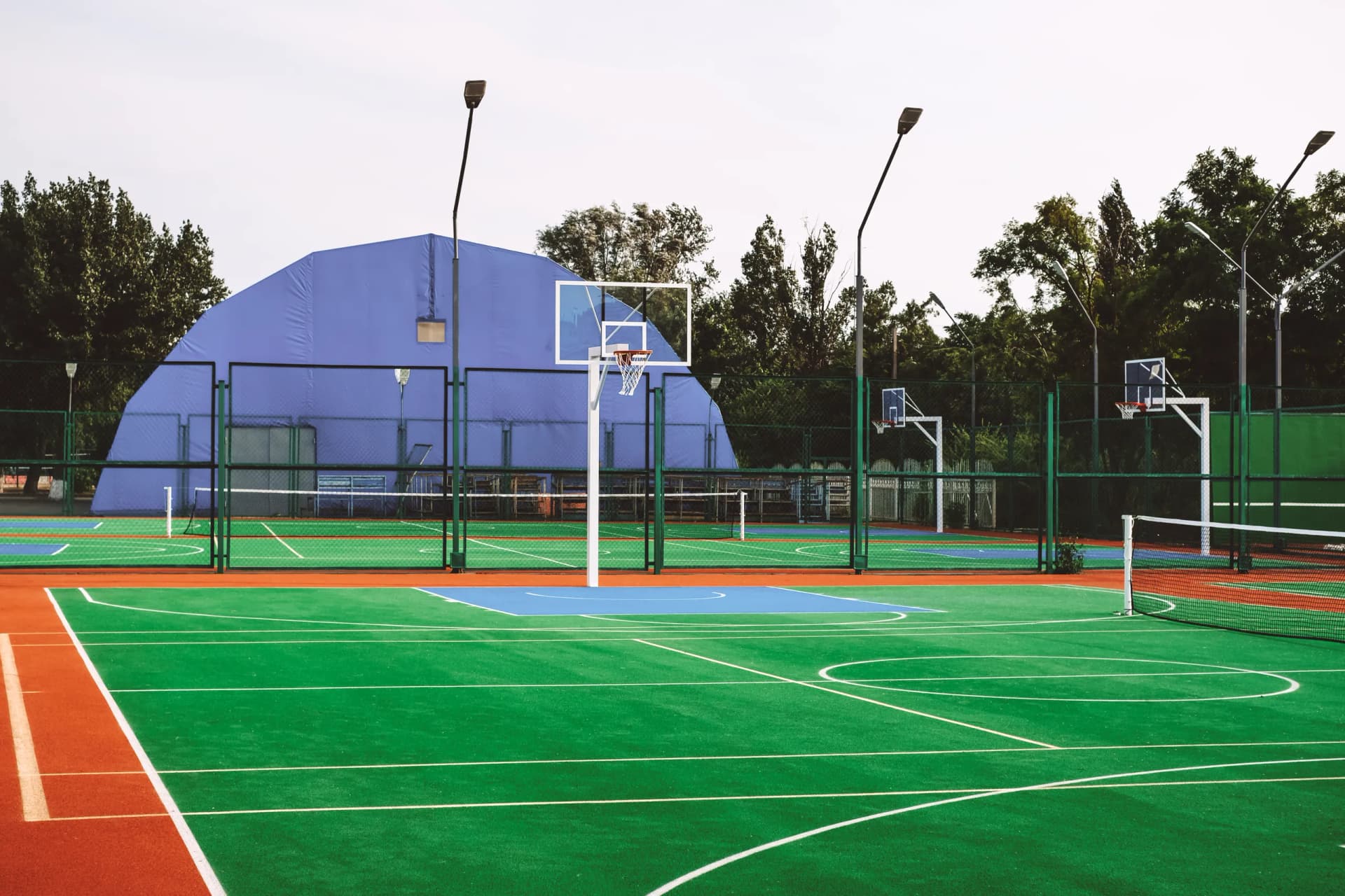 Multi-sport court with overlapping line markings for basketball, pickleball, and volleyball on a shared surface.
